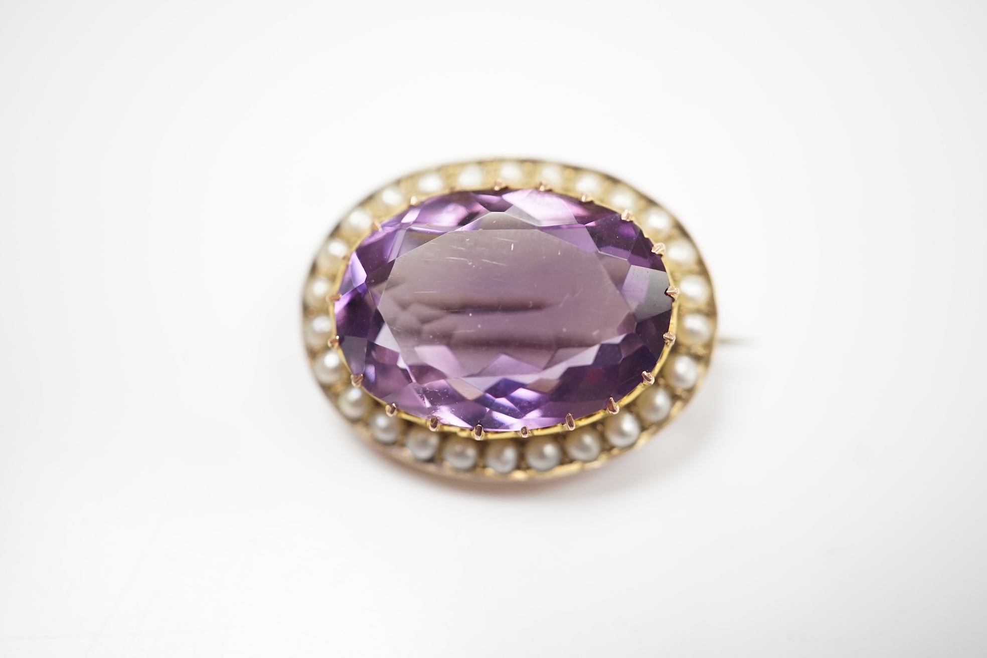 A mid 20th century 9ct and single stone oval cut amethyst set pendant brooch, with seed pearl border, 24mm, gross weight 4.8 grams. Condition - fair to good